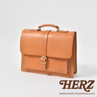 一個 tan 色皮革手提包，配有單扣和皮帶封口，以及頂部提把。