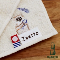 米白色精梳棉方巾，繡有卡通小狗圖案，並附有「Zootto」品牌標籤。