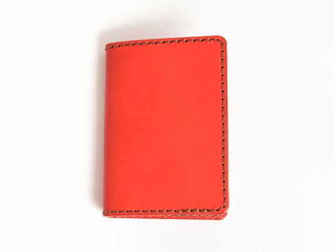 鮮紅色皮革製成的卡片收納夾，以對比色縫線手工縫製，設計簡潔，無其他配件。