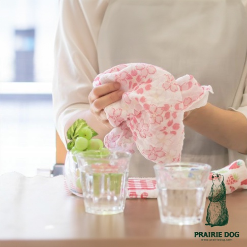 雙手拿著粉色櫻花圖案的五層紗質地擦拭巾，質地輕薄柔軟。