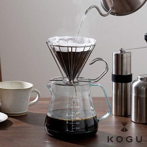 日製Tritan可微波耐熱咖啡壺，附有金屬濾網架，壺身為透明玻璃材質，刻有毫升刻度，手柄為藍色。咖啡壺內裝有滴漏咖啡，旁邊擺放著咖啡杯與磨豆機。