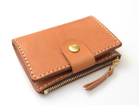 職人手作皮革拉鍊零錢鑰匙包，淺棕色牛皮材質，配有黃銅按扣和拉鍊，縫線清晰，設計簡約。