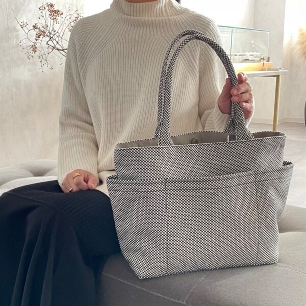 一手提托特包，採用黑白棋盤格紋的三河木綿刺子織材質，配有雙提把和外部口袋。