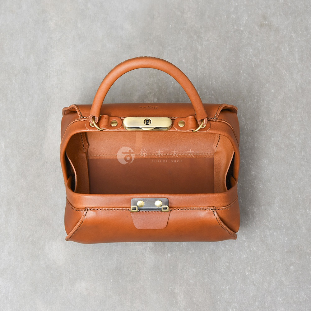 棕色皮革製成的手提包，配有金色口金鎖和提把，包身結構方正，展現職人手作質感。