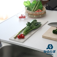 長形白色珪藻土吸水置物墊上擺放著綠色蔬菜、蘆筍及兩顆小番茄。