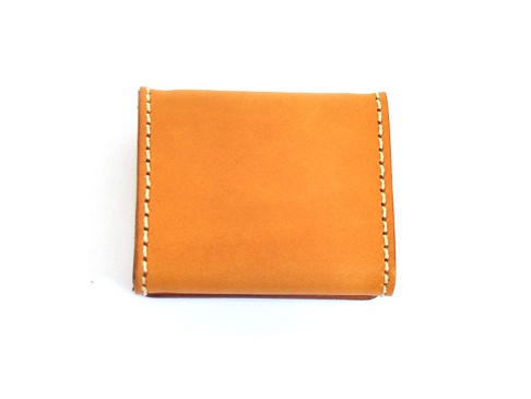 職人手作皮革箱型收納零錢包，採用天然皮革材質，呈現溫潤的焦糖棕色，邊緣以米白色縫線手工縫製，設計簡約實用。