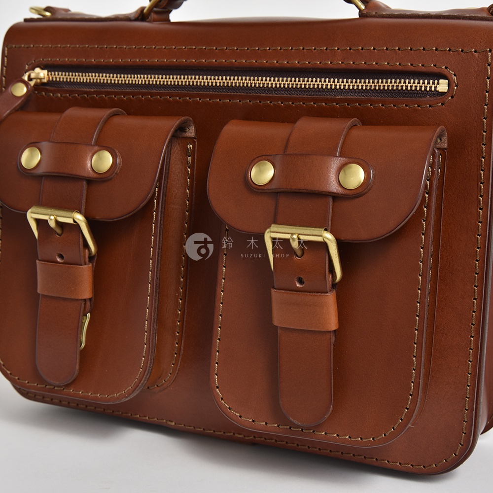 職人手作棕色皮革雙口袋單肩包，配有黃銅釦環和拉鍊，風格經典。