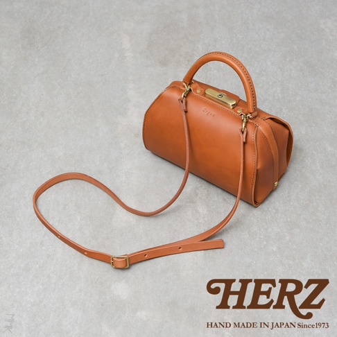 棕色皮革製成的職人手作 Organ 兩用口金手提包，附有可調節長度的斜背帶。包包設計簡潔，帶有復古的口金開合和提把，展現皮革的自然質感。