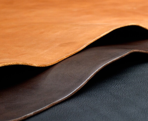 三種不同質感的皮革，由上而下分別是駝色、棕色和黑色，呈現堆疊的視覺效果。