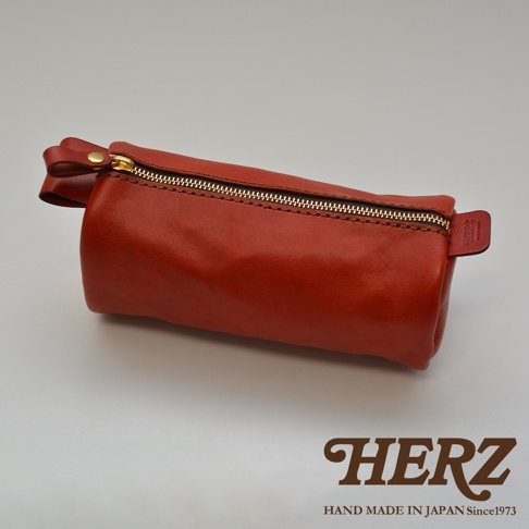 職人手作皮革多用途收納筆袋，採用光滑棕紅色皮革製成，配有金色拉鍊和皮革拉環，整體呈現圓筒狀。