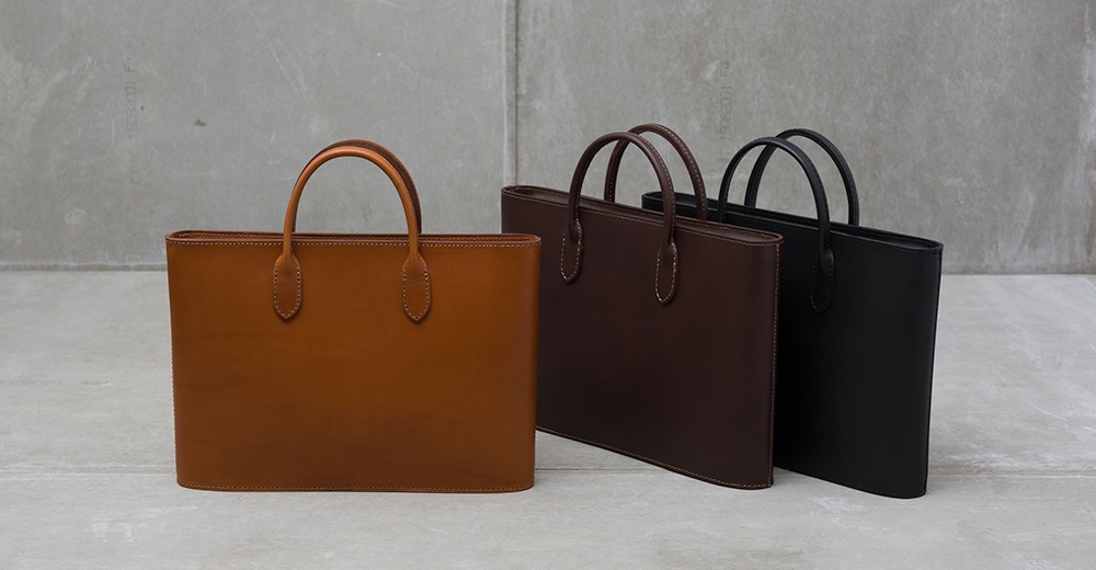 三款職人手作皮革Organ薄型公事包，分別為棕褐色、深棕色與黑色，皆配有同色系皮革提把。