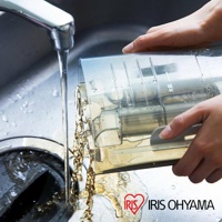 透明塑膠材質的織物清潔機水箱，傾斜於水槽中，水從水龍頭流下，同時水箱中的髒水也傾倒出來。