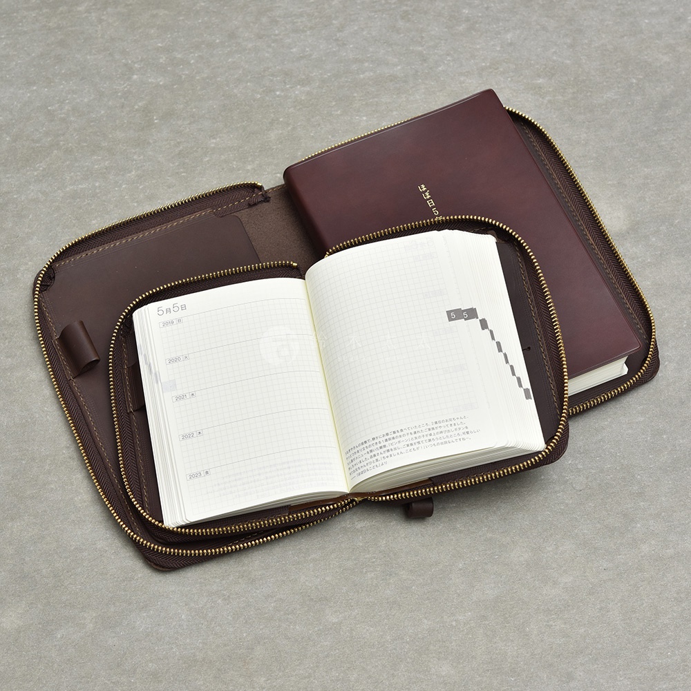 精緻的職人手作皮革收納包，打開後可見一本筆記本，筆記本內頁印有日期和格子。