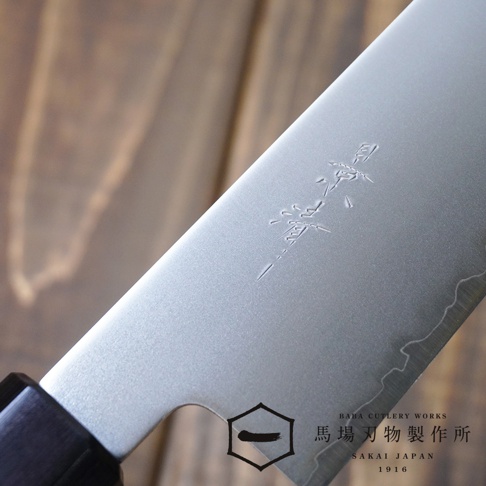 [景清] Chromax鋼三德刀，18cm刀刃，表面有品牌刻印，刀柄為深色木質。