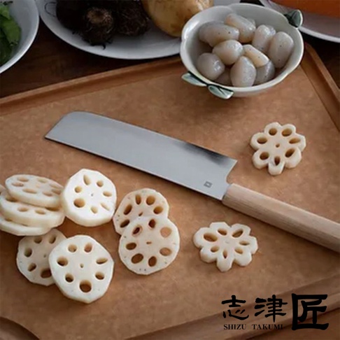 Yuri 菜切刀，銀色不鏽鋼刀刃，淺木色刀柄，一旁擺放著切成圓片和花狀的蓮藕，刀身部分壓印有品牌標誌。