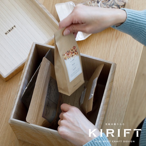 桐木調濕儲米箱，自然木紋，箱內裝有數包標示著「Peach」等字樣的紙袋包裝物，一隻手正將其中一包放入箱內。