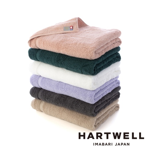 一疊由上至下分別為粉紅色、深綠色、白色、淺紫色、炭灰色和米色六種顏色的今治毛巾，材質看起來為柔軟的棉質，頂端粉紅色毛巾上可見品牌標籤。