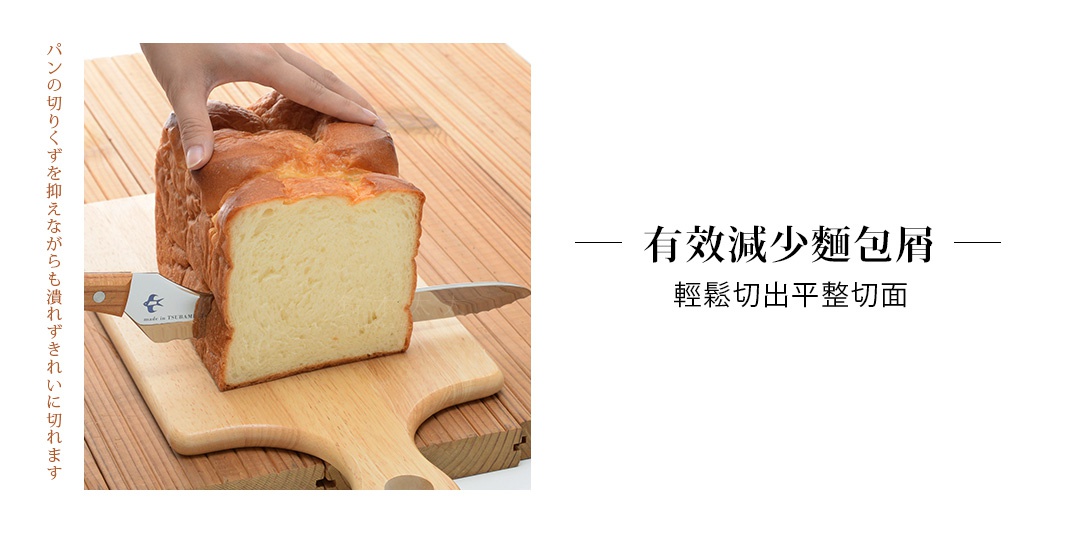 不鏽鋼麵包刀正在切一塊金黃色的吐司麵包，刀柄為木質，刀片上有鳥形圖案和「made in TSUBAME」字樣。麵包放在木製砧板上，背景為木紋。