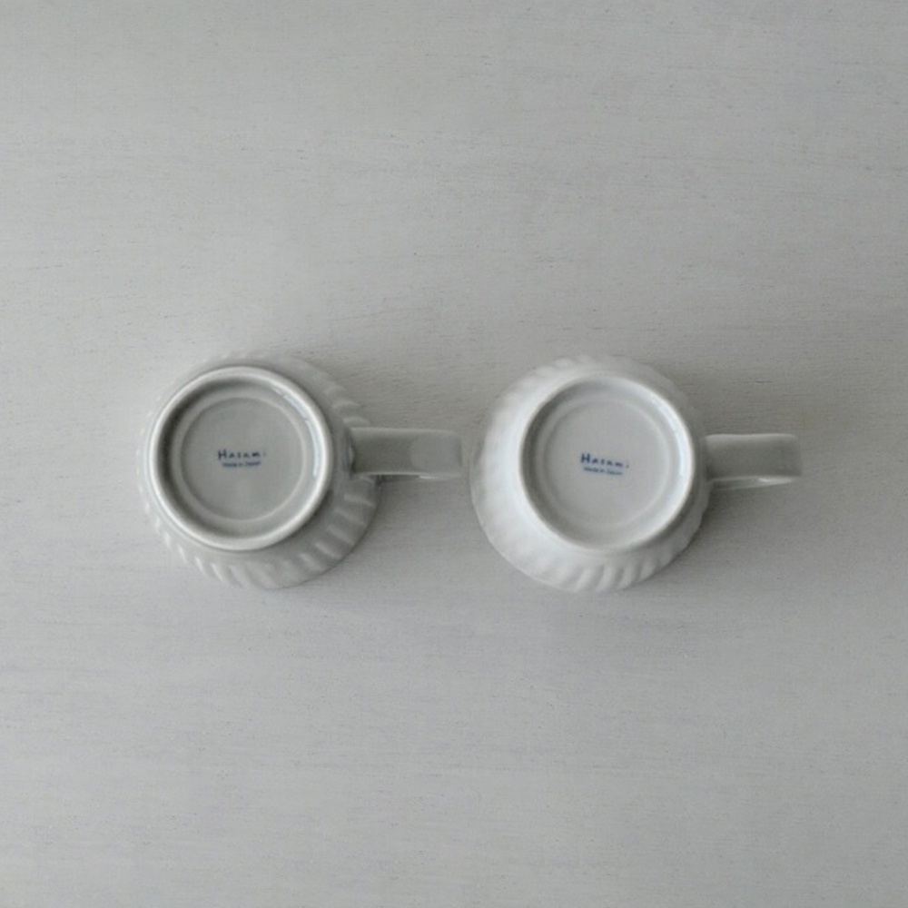 兩個淺灰色波佐見燒 FUWARI 馬克杯，杯底朝上，呈現漩渦狀壓紋，杯身有品牌標誌。