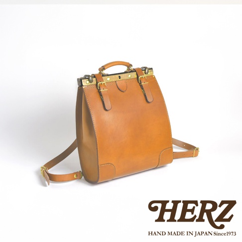 棕色皮革復古口金後背包，配有金色金屬扣環和可調式肩帶，上方有提把。