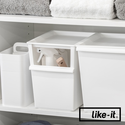 白色塑膠製可堆疊窄型整理收納盒，正面有一個較小的開放式收納空間，內有噴霧瓶和木柄清潔刷。