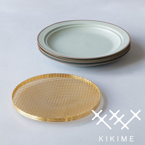 一套淺綠色美濃燒疊放的餐盤，盤緣有褐色邊線。下方有一個圓形金色金屬網瀝油架，網格細密。