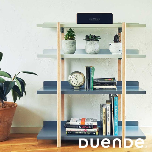 MARGE SHELF 4 四層置物收納架，採用灰藍色金屬層板與淺木色支架，層板上擺放著盆栽、時鐘、書籍及藍牙喇叭。