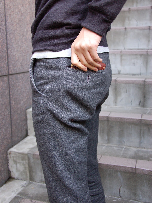 一名男子將一個棕色皮革短夾放入灰色長褲的後口袋。