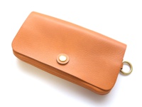 橘色皮革長夾，帶有金色按扣和側邊金屬環，適合旅行使用，多層次收納設計。