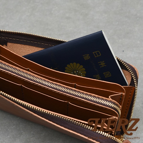職人手作皮革Organ大容量拉鍊長夾，內部可見一個深藍色護照，護照上有金色菊花紋章及日文文字，長夾內部隔層清晰，拉鍊為金色。