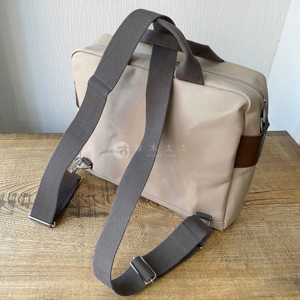 犬印純綿帆布三用橫式側背包，米色帆布材質，搭配咖啡色皮革飾邊，設有兩條灰色織帶提把及一條可拆卸調整的灰色長背帶。