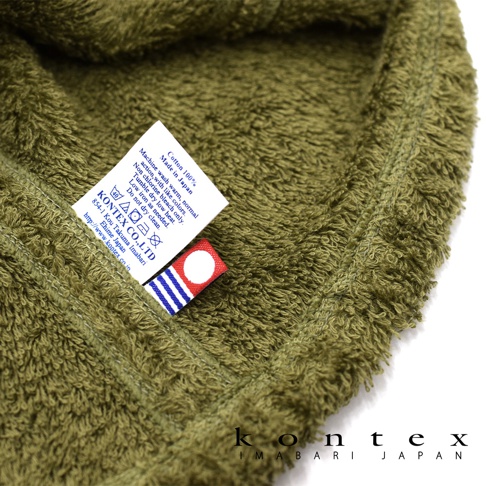 橄欖綠色、觸感柔軟的毛巾材質，帶有縫製的品牌標籤，標籤上印有「KONTEXT CO., LTD」及洗滌說明。