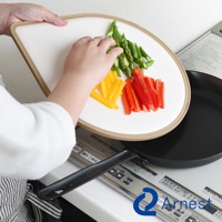 淚滴型抗菌料理砧板，白色表面，帶有淺褐色邊框，上面擺放著切好的蘆筍、黃甜椒和紅甜椒。