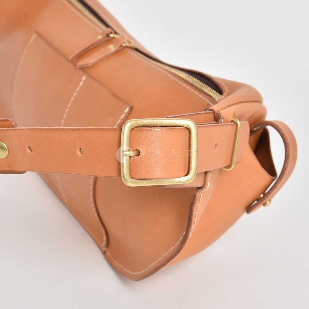 HERZ 職人手作皮革大容量斜背包 F-1 的細節，展示了其 tan 色皮革、黃銅扣環和縫線細節