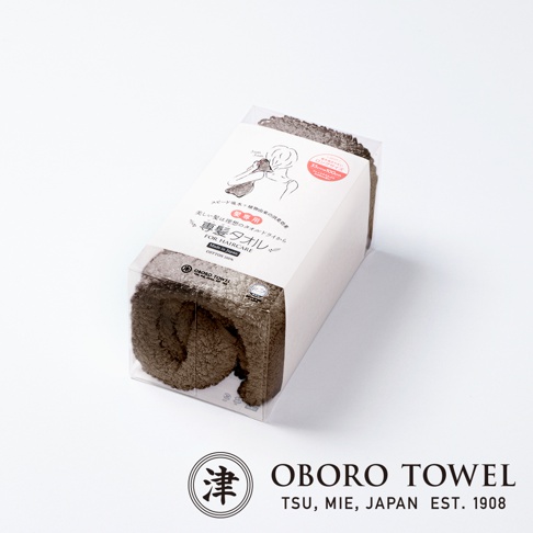 一條捲起的棕色髮專用毛巾，材質為棉，包裝盒上印有日文和英文說明，以及品牌 Logo。