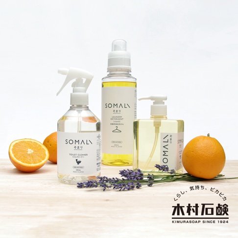 SOMALI 泡沫式馬桶清潔劑 300ml，透明瓶身搭配白色噴頭，瓶身標籤為白色，印有品牌名稱及產品資訊。旁邊擺放著一瓶黃色液體的洗衣精，以及一瓶透明液體的洗手液，另有半顆橘子、一顆完整橘子及一小束薰衣草裝飾。