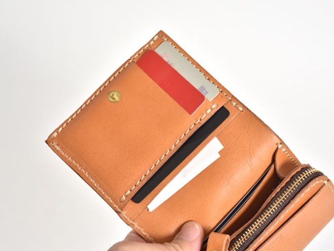 職人手作皮革直式卡片收納雙折短夾，淺棕色牛皮材質，做工細緻，內有卡片插槽，可放置多張卡片，搭配黃銅壓扣與拉鍊。