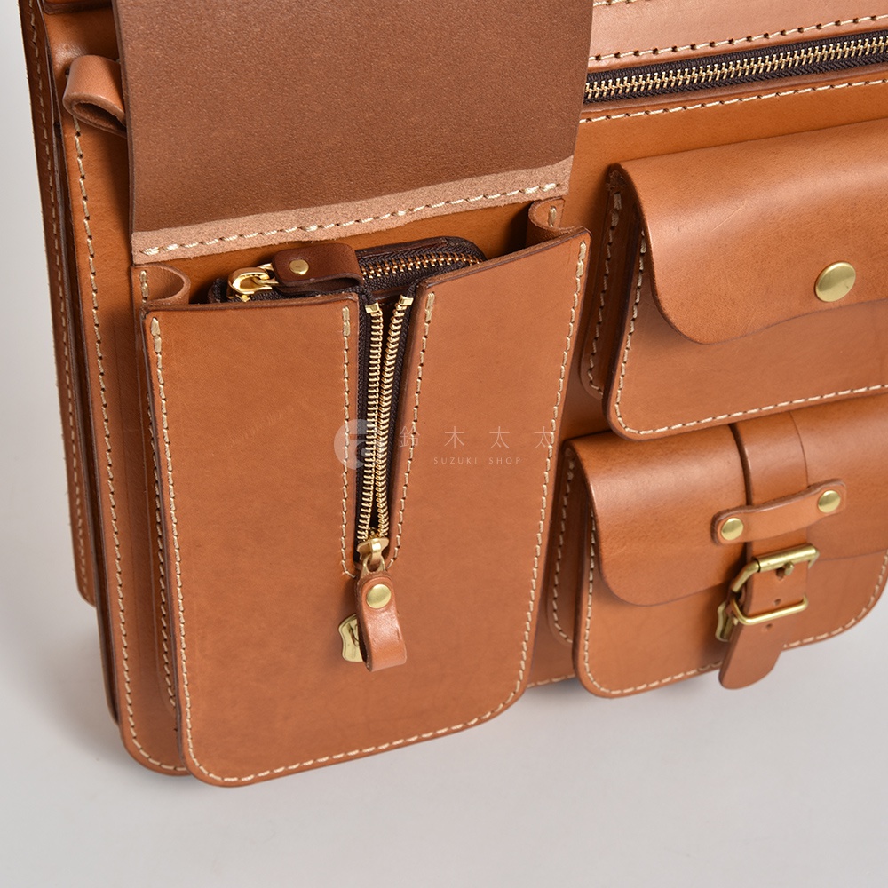 職人手作皮革三口袋三用後背包，展現自然棕色皮革紋理，搭配金色拉鍊與銅扣，設計簡約實用。