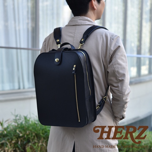 黑色職人手作皮革兩用後背包，配有金色拉鍊和搭扣，展現簡約俐落的商務休閒風格。