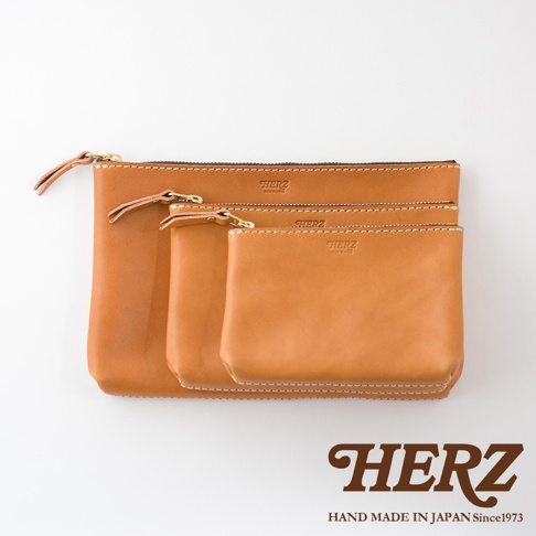 三款不同尺寸的淺棕色皮革長方形拉鍊收納包，皆有品牌烙印與縫線細節，搭配金屬拉鍊與皮革拉頭。