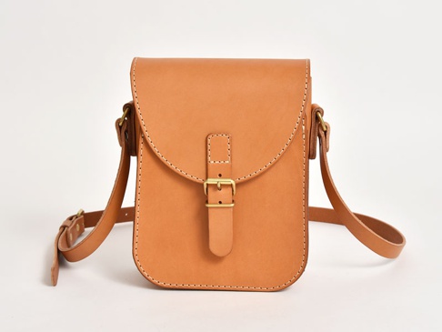 職人手作皮革翻蓋迷你單肩包，採用天然棕色皮革製成，設有黃銅色搭扣和可調節肩帶，風格簡約。