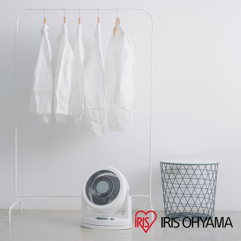 白色IRIS OHYAMA PCF-HM23 空氣循環扇，機身帶有控制按鈕，前置扇網為灰色螺旋紋，擺放在白色衣架和綠色網狀置物籃旁。