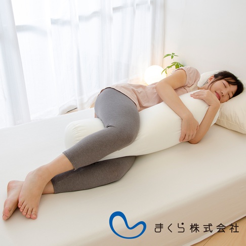 一位女性側臥，雙腿夾著一個白色圓柱形夾腿枕，枕頭材質柔軟，呈現出舒適的支撐感。