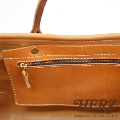 職人手作皮革托特包，採用棕色皮革，設有拉鍊內袋和按扣。縫線清晰，質感良好。