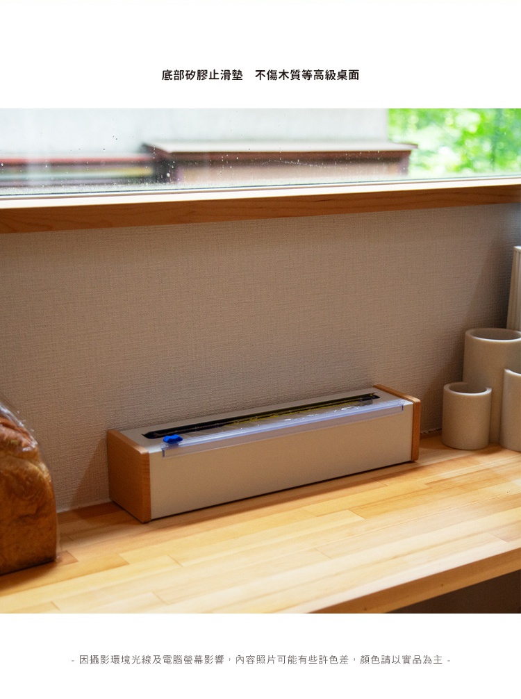 日本製原木鋼製保鮮膜切割器，主體為淺灰色鋼板，兩側飾以原木邊框，頂部有透明切割導槽，藍色按鈕。