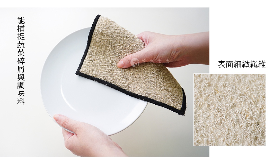 一塊米白色、帶有黑色滾邊的抹布，正在擦拭白盤，右側顯示抹布的細纖維特寫，左側有中文標語「能捕捉蔬菜碎屑與調味料」，右側有中文標語「表面細緻纖維」。