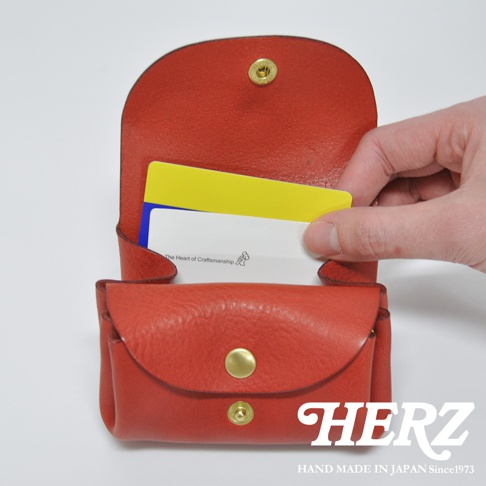 紅色皮革三層收納零錢包，內有黃色與白色卡片，包款有金色釦子，材質為皮革。