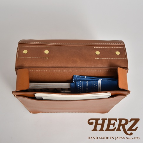 職人手作皮革三口袋三用後背包A-19-R，展現棕色皮革紋理，內部收納雜誌與藍色印花頭巾，並有金色金屬釦飾。