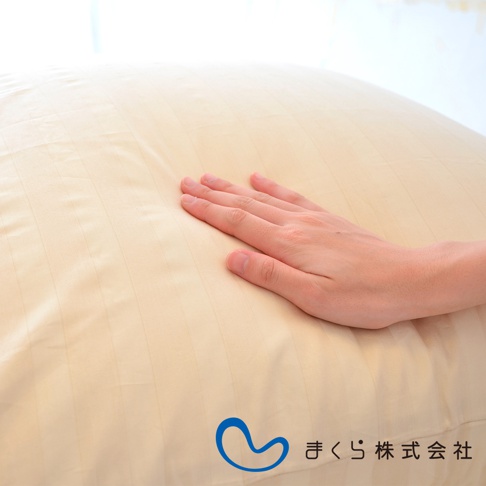 淺米色條紋枕套，材質為柔軟親膚的布料，左側有一隻手輕柔地觸碰枕套表面，展現其細緻的紋理與彈性。