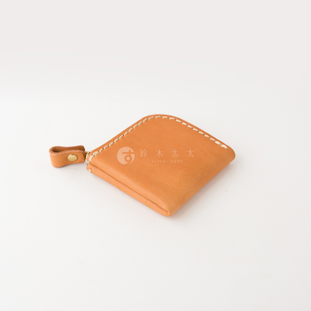 一個棕褐色的日本HERZ手工皮革零錢包，表面採用Stare皮革製作，呈現簡約的方形圓角設計，邊緣以淺色縫線細緻縫合，側面附有一個帶有金屬扣的皮革拉鍊拉環，整體質感細膩且充滿職人手作風格。